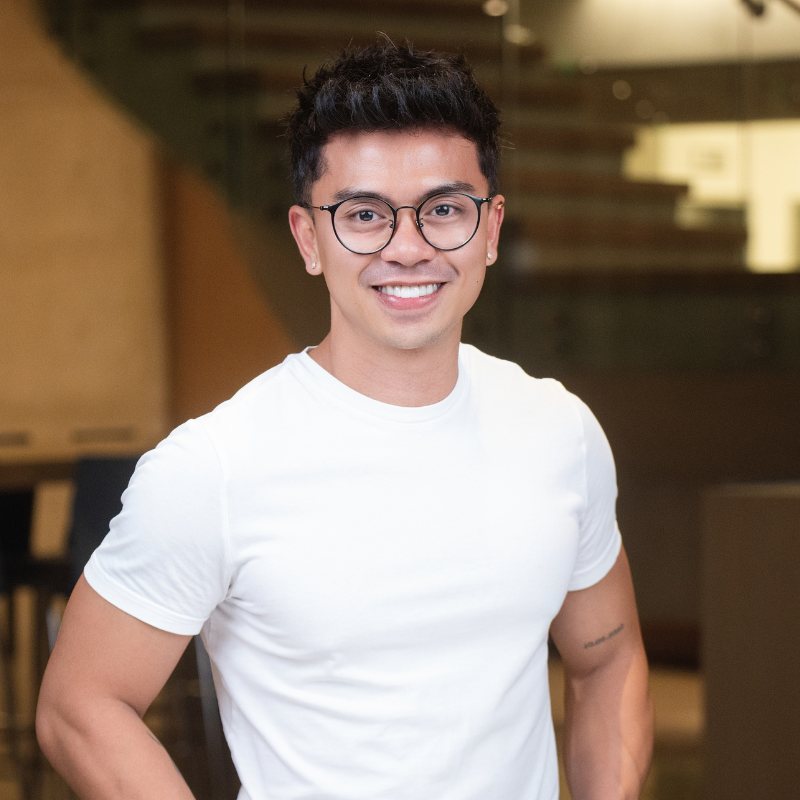 Les Balibat smiling, wearing glasses and a white t‑shirt